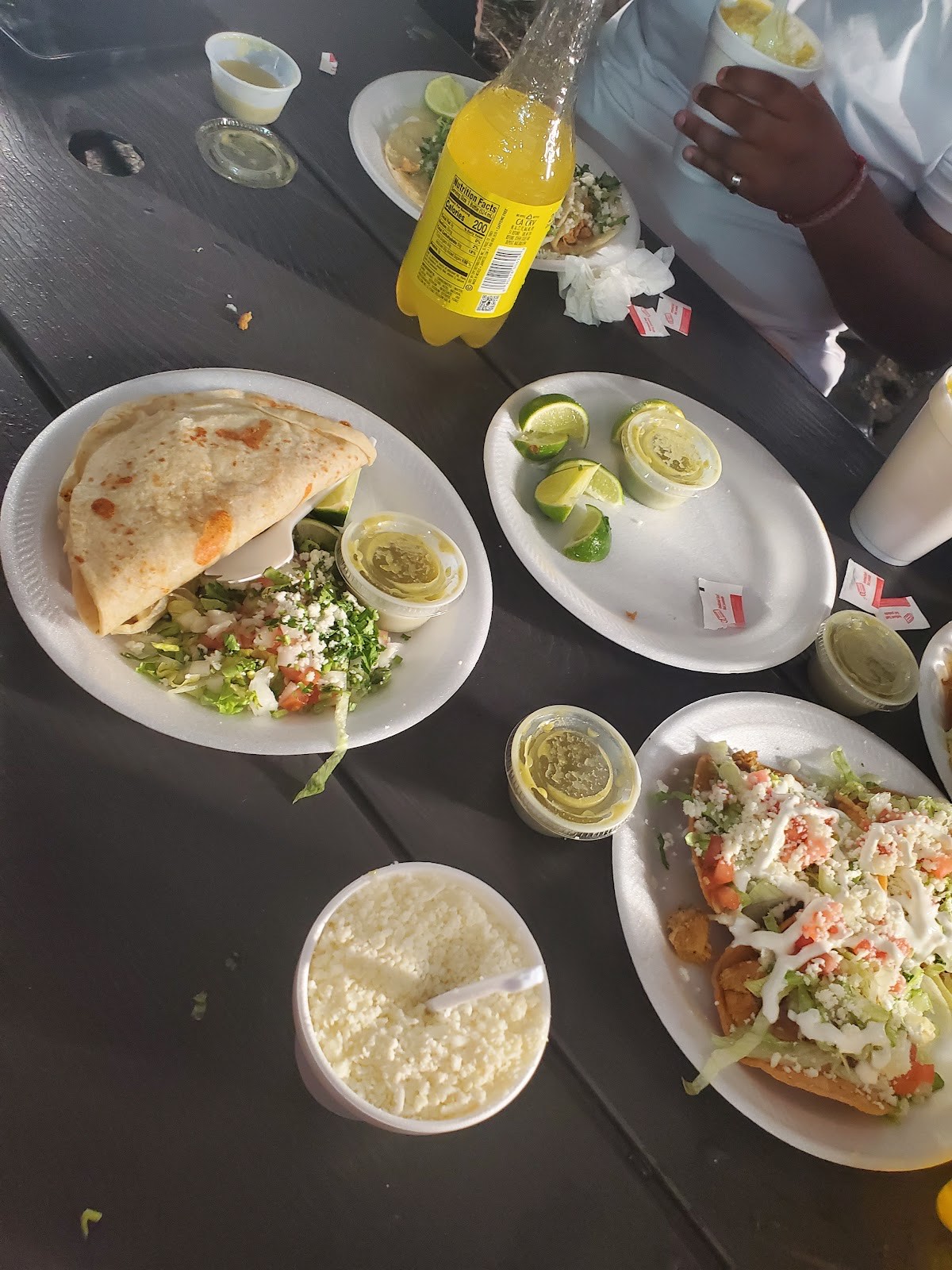 A picnic-table spread of Gueros quesadillas, tostadas, elote, fresh salad and Jarritos soda
