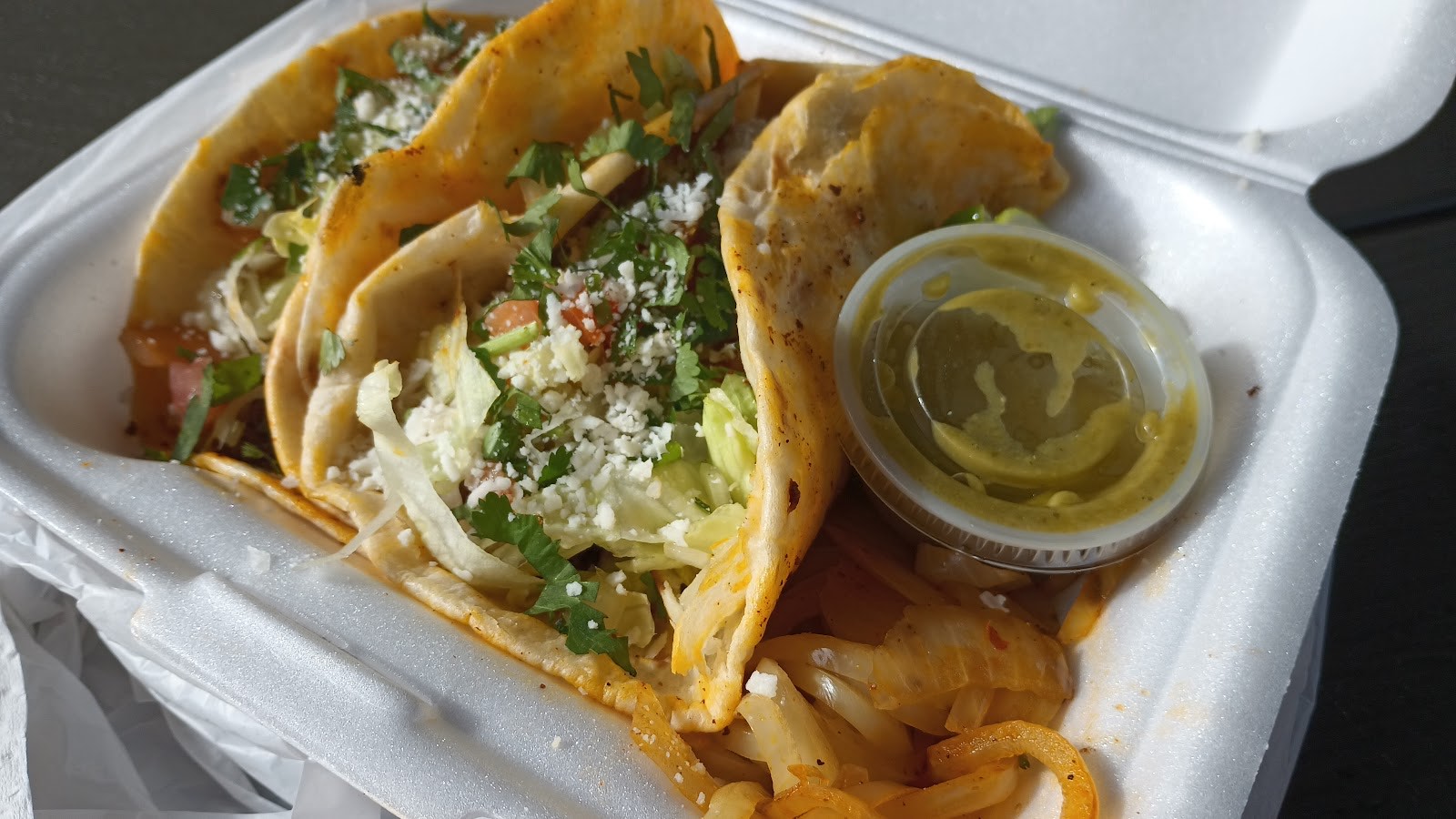 Three Gueros street tacos packed with meat, cilantro, onion, queso fresco and a cup of salsa verde